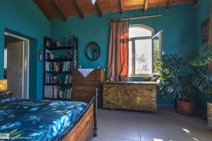 a bedroom with blue walls and a bed and a window at Strongilos Homestay in Velanidia