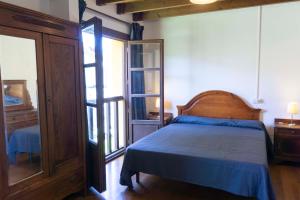 a bedroom with a bed with a blue bedspread and a window at Casa El Collau Norte in Porrúa