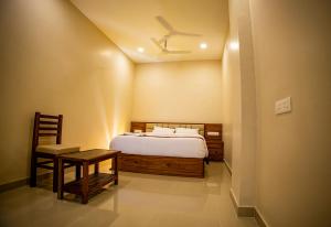 a bedroom with a bed and a table and a ceiling at KKM International in Kuzhittura