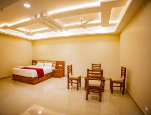 1 dormitorio con 1 cama, mesa y sillas en KKM International en Kuzhittura