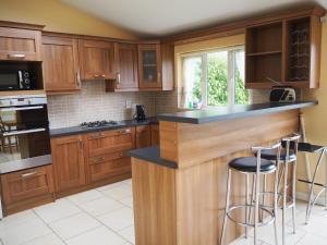 a kitchen with wooden cabinets and a island with bar stools at The Walkinstown Property in Dublin