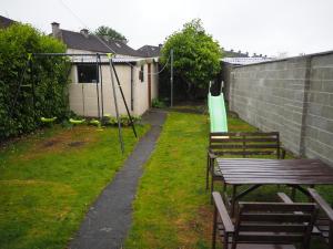 un patio trasero con mesas y sillas y un parque infantil en The Walkinstown Property, en Dublín