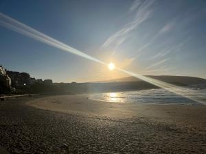 a beach with the sun setting on the water at Apartamento Arao Malpica con vistas al mar in Malpica