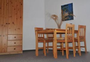 Pension Sassnitz Atelierhaus في ساسنيتز: طاولة غرفة طعام خشبية مع كرسيين وخزانة
