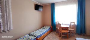 a bedroom with a bed and a table and a window at Willa Zacisze Sianożęty in Sianozety