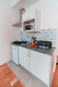 een keuken met een wastafel en een magnetron bij Harbour49 - AVEIRO FLATS & SUITES in Aveiro