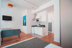 cocina con paredes blancas y silla azul en una habitación en Harbour49 - AVEIRO FLATS & SUITES en Aveiro