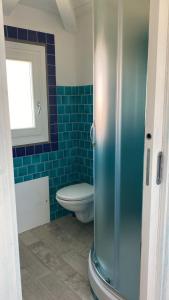 a bathroom with a toilet and a blue tiled wall at Stella Marina in Olbia