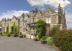 Un vieux bâtiment avec des drapeaux devant lui dans l'établissement Best Western Walton Park Hotel, à Clevedon