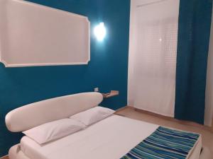 Cama blanca en habitación con pared azul en Casa Amy en San Michele Salentino