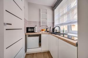 uma cozinha com armários brancos e um balcão com um micro-ondas em Central Platinum Apartments 20 em Rybnik