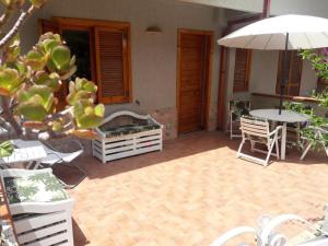 een patio met een tafel en stoelen en een parasol bij Appartamento Airone in Piraino