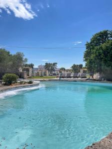 a pool of blue water with buildings in the background at Masseria Piccole Taverne in Ostuni
