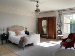 a bedroom with a bed and a chair and a mirror at Stylish elegant two bedroom apartment overlooking Southsea Common and the Solent in Portsmouth