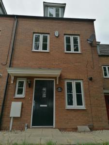 a brick house with a black door and windows at Agnes House in Grimsby