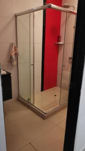 a glass shower in a bathroom with a red wall at Casa amazilia in Leticia +4 photos
