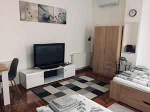 a living room with a flat screen tv on a white cabinet at Déri Kert Apartmanház B in Baja
