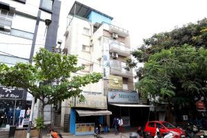 a tall building on a city street with trees at Avenue Inn in Bangalore