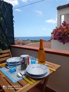 uma mesa com pratos e uma garrafa de vinho na varanda em EOS 17 em Palizzi Marina