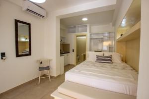 a bedroom with a large white bed and a chair at KyMa Studios and Suites in Asprovalta