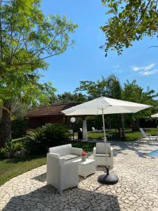 a patio with a white umbrella and a couch and chair at Villa Paradiso in Latiano