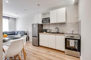 una cocina con armarios blancos y una mesa con sillas. en Central Platinum Apartments 15, en Rybnik