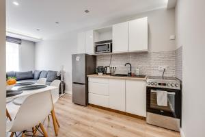 Una cocina con gabinetes blancos y una mesa con sillas. en Central Platinum Apartments 15, en Rybnik