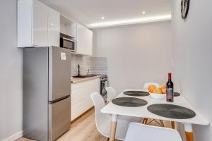 a white kitchen with a white table and a white refrigerator at Central Platinum Apartments 15 in Rybnik
