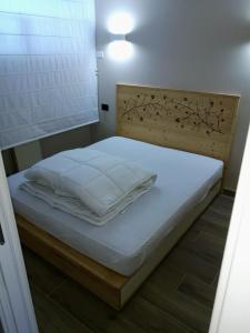 a bed with white sheets and a wooden headboard at Appartamento Condominio Carlo Magno Folgarida Alta in Folgarida