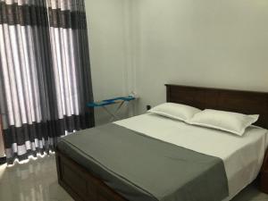 a bedroom with a large bed with white sheets and pillows at Happy Homes in Kiribathgoda