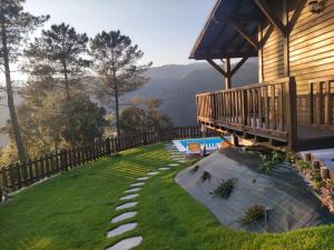 a house with a deck and a lawn with a view at Quinta da Resteva-Chalé do RIBEIRO in Vieira do Minho