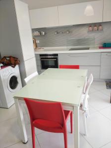 a kitchen with a white table and red chairs at appartamento openspace fronte mare esclusivo due letti matrimoniali a Portovenere in Portovenere