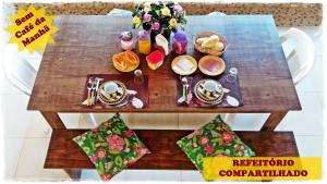 Suítes de Setiba - HOSPEDARIA OCA RUCA في غواراباري: طاولة خشبية عليها طعام ومشروبات