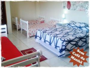 1 dormitorio con 2 camas individuales y 1 silla en Suítes de Setiba - HOSPEDARIA OCA RUCA, en Guarapari