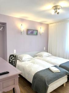 - 2 lits dans une chambre avec une table et un bureau dans l'établissement Hôtel D’Artiste, à Pierrefontaine-les-Varans