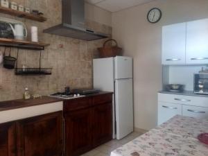 a kitchen with a white refrigerator and wooden cabinets at Les Jardins d'Arbousse in Saint-Jean-du-Gard