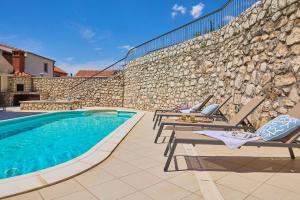 una piscina con sillas y una pared de piedra en Hedera Estate, Villa Hedera IX en Banići