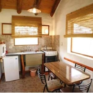 a kitchen with a table and a sink and a stove at Cabanas Parparim in Mina Clavero +14 photos