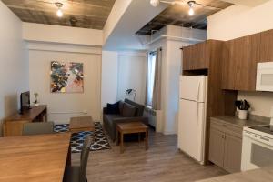 a kitchen and living room with a couch and a refrigerator at Le Central in Rouyn