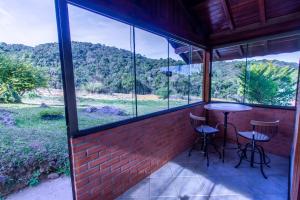 a screened in porch with a table and two stools at Chales Estrada de Chão in Monte Verde
