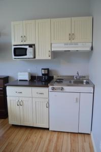 a kitchen with white cabinets and a stove and a sink at Le Citadin in Rouyn-Noranda