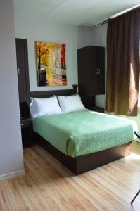 a bedroom with a bed with a green comforter at Le Citadin in Rouyn-Noranda