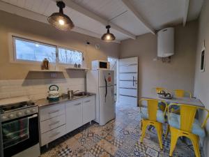 a kitchen with a refrigerator and a table with yellow chairs at La Vikinga in Buenos Aires