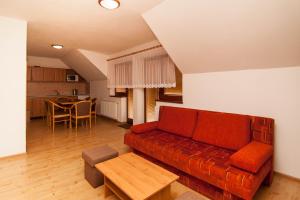a living room with a red couch and a table at Apartmány Ďurik in Liptovský Mikuláš