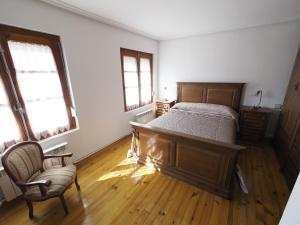 a bedroom with a bed and a chair and two windows at CASA PURI - ACOGEDORA CASA CON PARKING y PATIO INTERIOR 