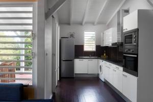 a kitchen with white cabinets and a stainless steel refrigerator at Villa Picasso in Sainte-Rose