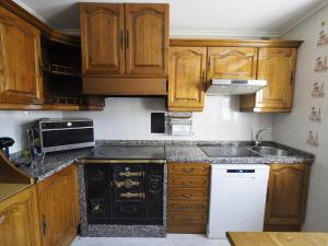 uma cozinha com armários de madeira e um forno com placa de fogão em CASA PURI - ACOGEDORA CASA CON PARKING y PATIO INTERIOR 