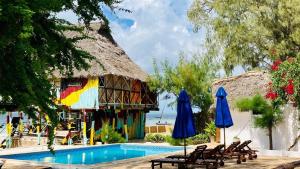 a resort with a swimming pool with chairs and umbrellas at Kaure Sand Beach Lodge in Uroa