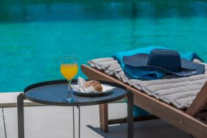 een glas wijn en een hoed op een tafel naast een zwembad bij Villa Gold Residence 1 in Mlini