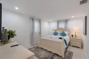 um quarto branco com uma cama com almofadas azuis em RENOVATED 2 Bd with Private Hot Tub 6 min to HARDROCK CASINO em Fort Lauderdale